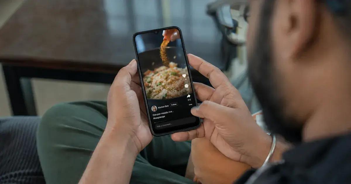 Photograph: indian adult scrolling a generic vertical short-video feed on a budget handset, in daylight.